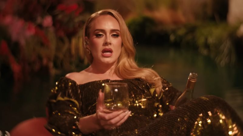 Adele gloriously floats down lazy river holding a glass of wine in new music video 
